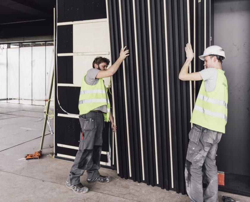 Installation d'un mur noir PETAC © recouvert de lattes de bois
